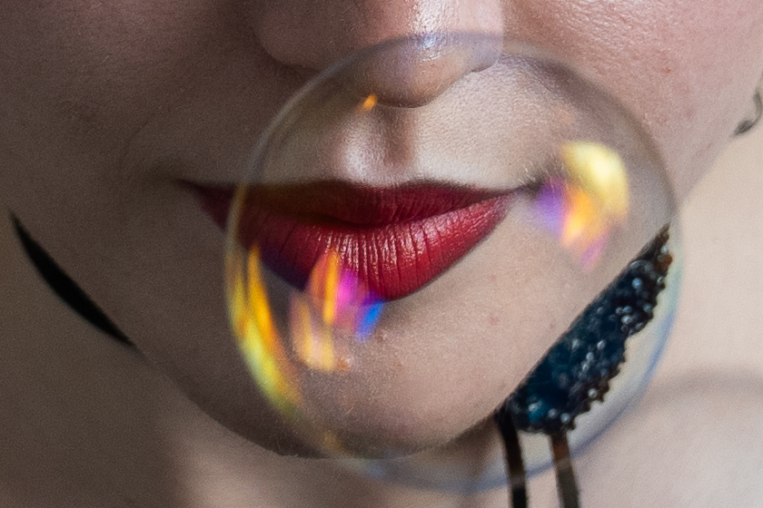 Detail — red lips behind a drifting soap bubble