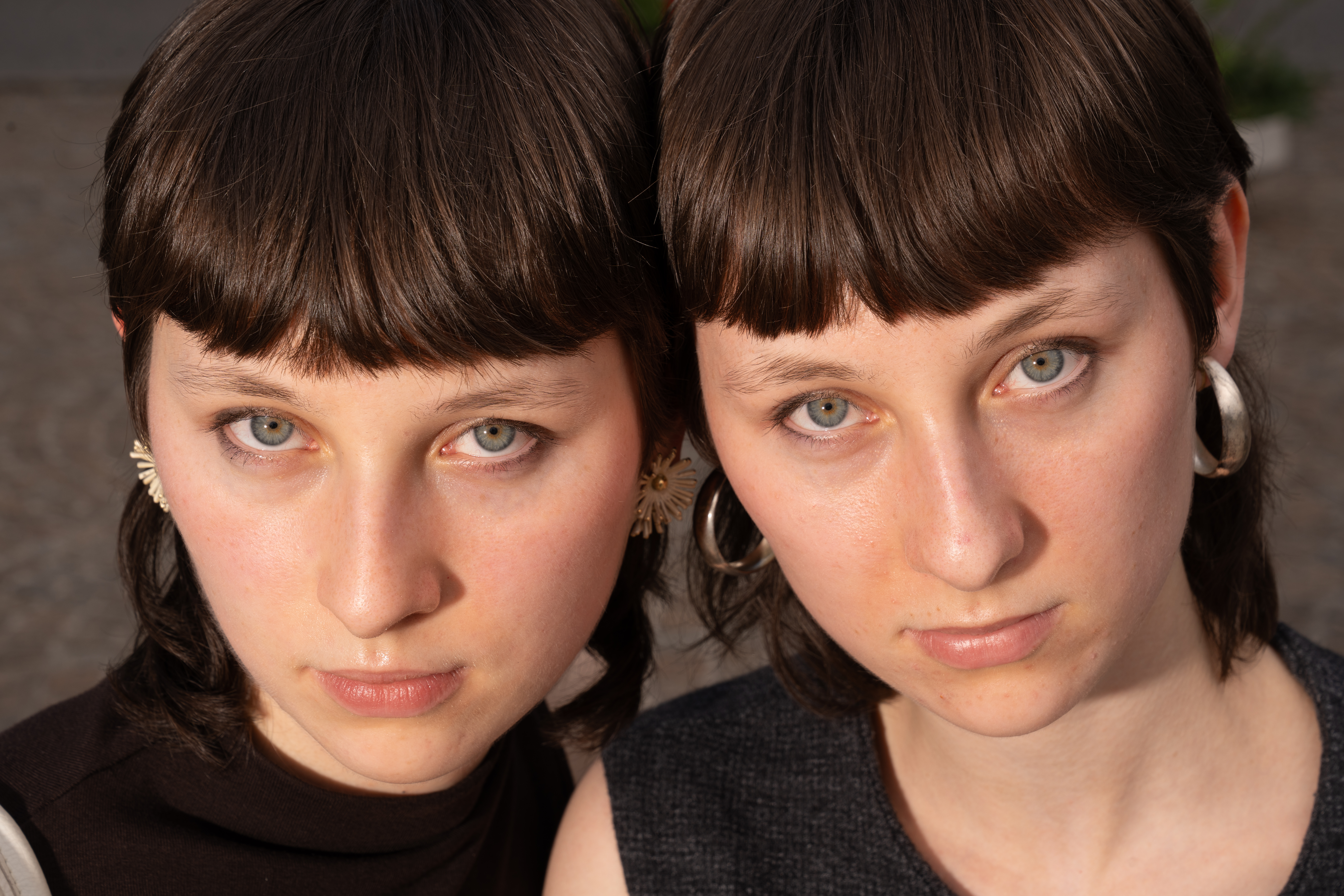 Close-up of twin sisters with matching fringes looking into the camera