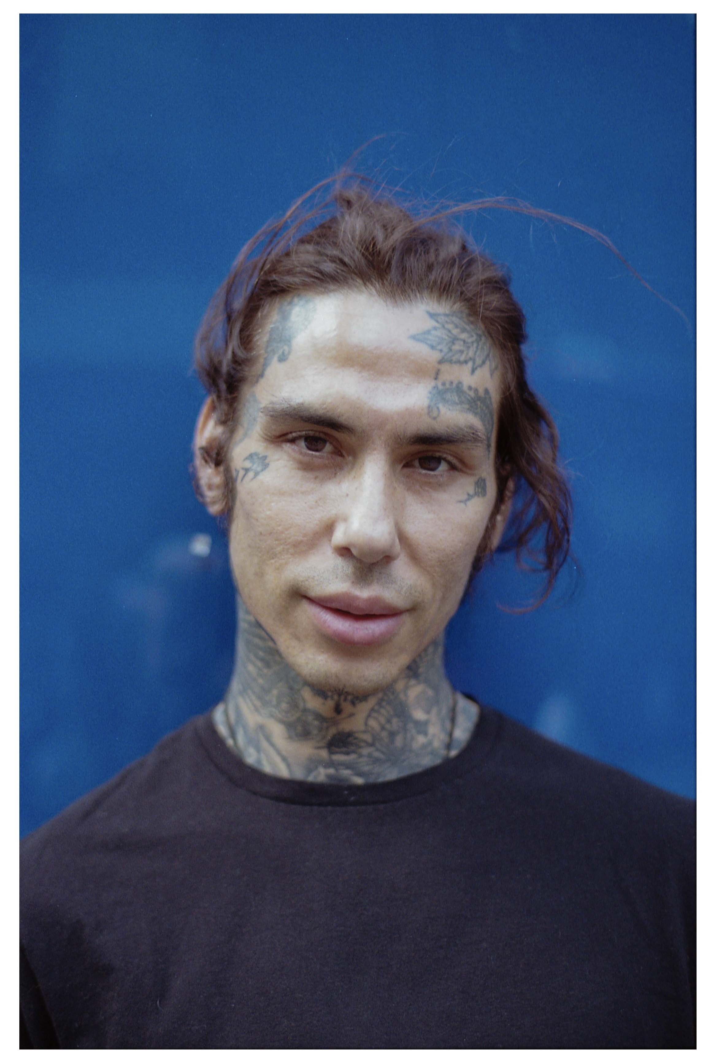 Portrait of a tattooed man against a blue wall — cover of the people series