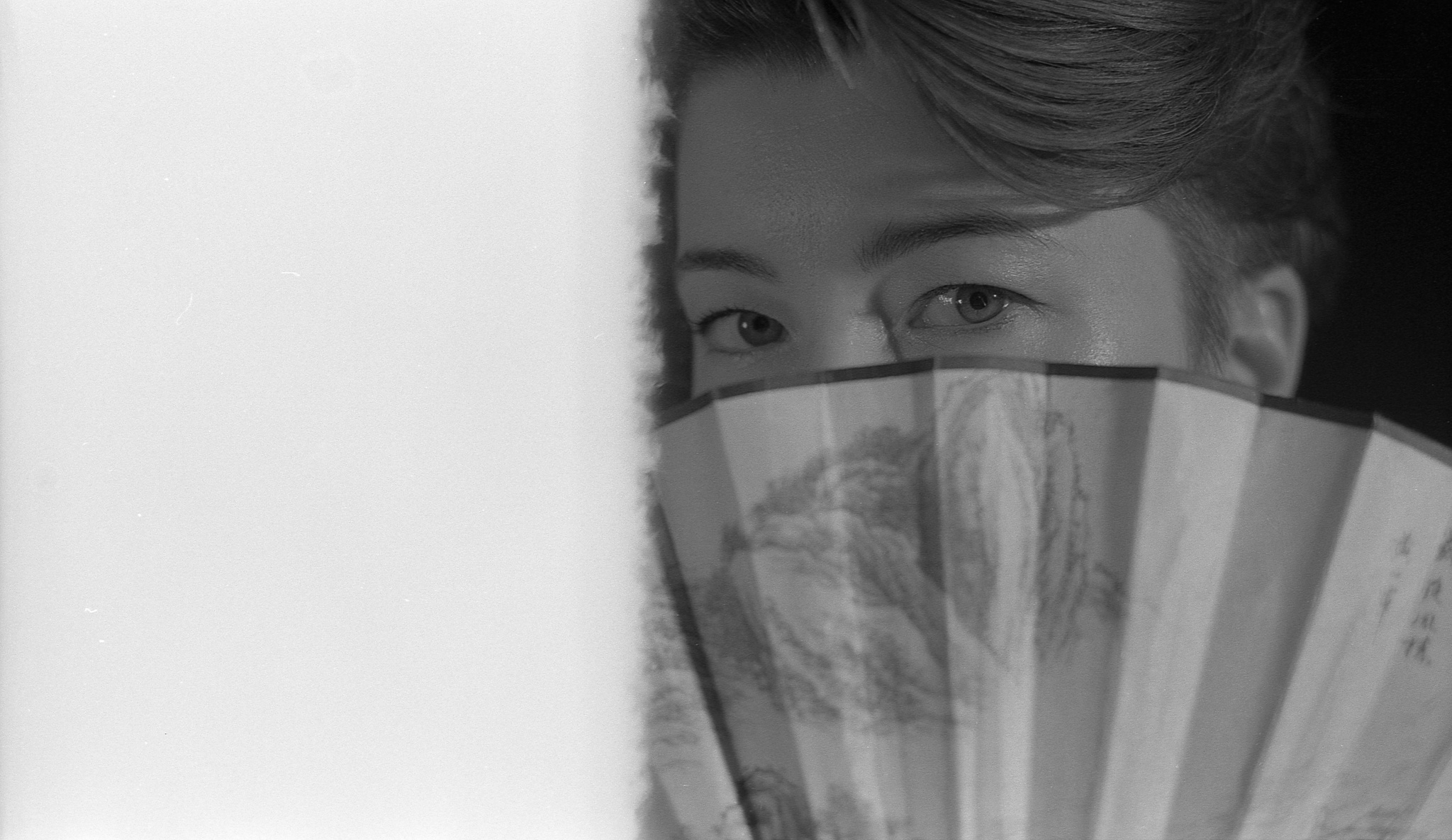 Yulia's eyes over a paper fan — black-and-white portrait