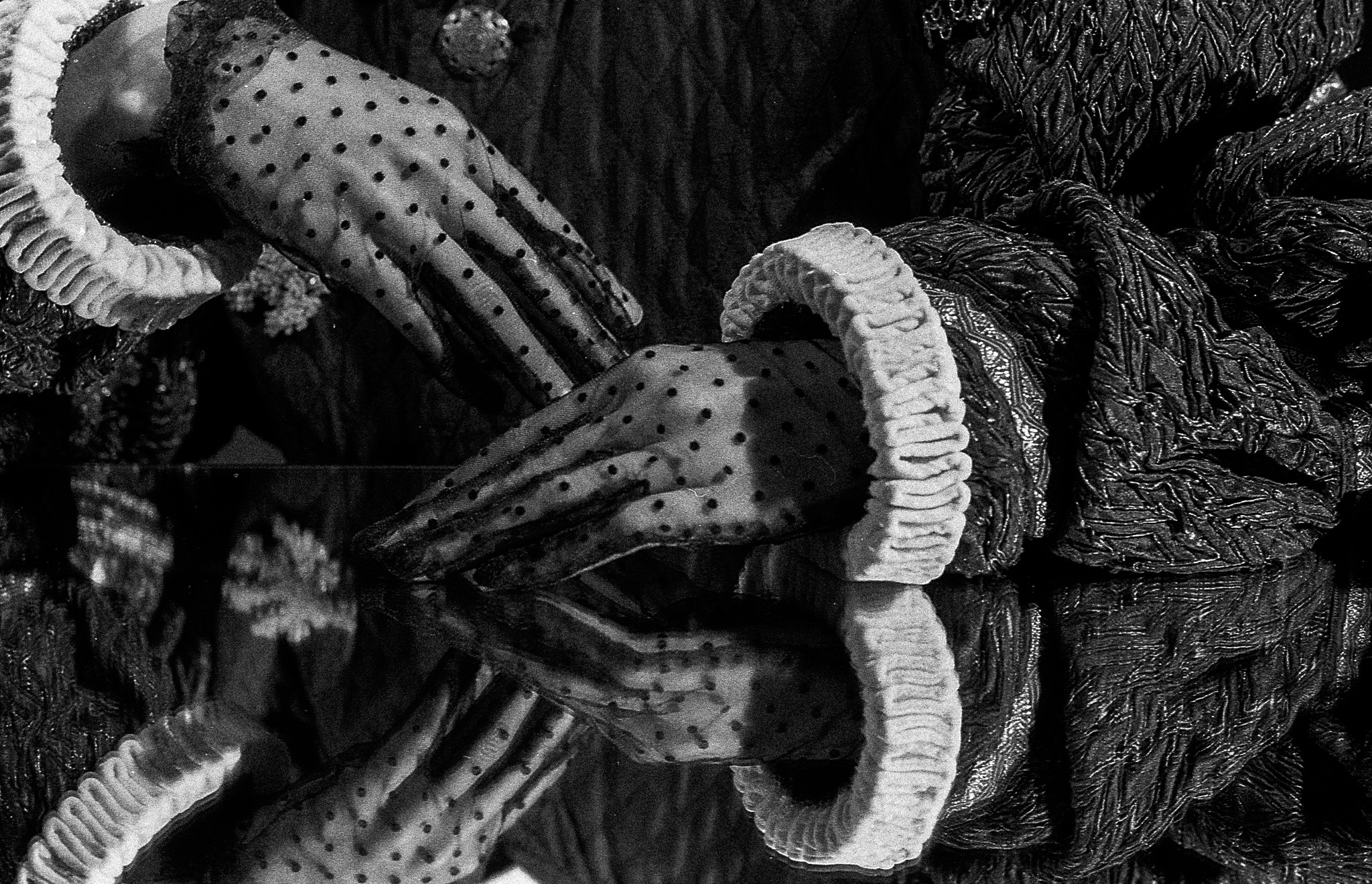 Gloved hands with ruffled cuffs meeting their reflection