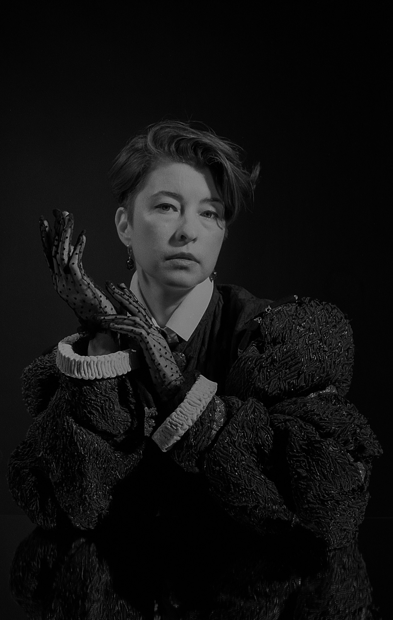 Yulia raising her hands in sheer polka-dot gloves, looking into the camera