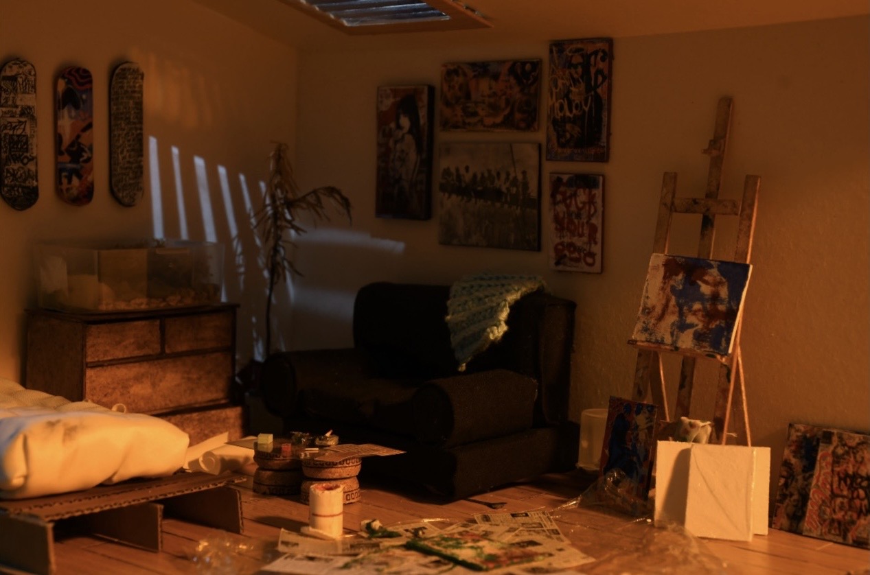 A miniature artist's atelier — tiny easel, sofa and paintings in warm light