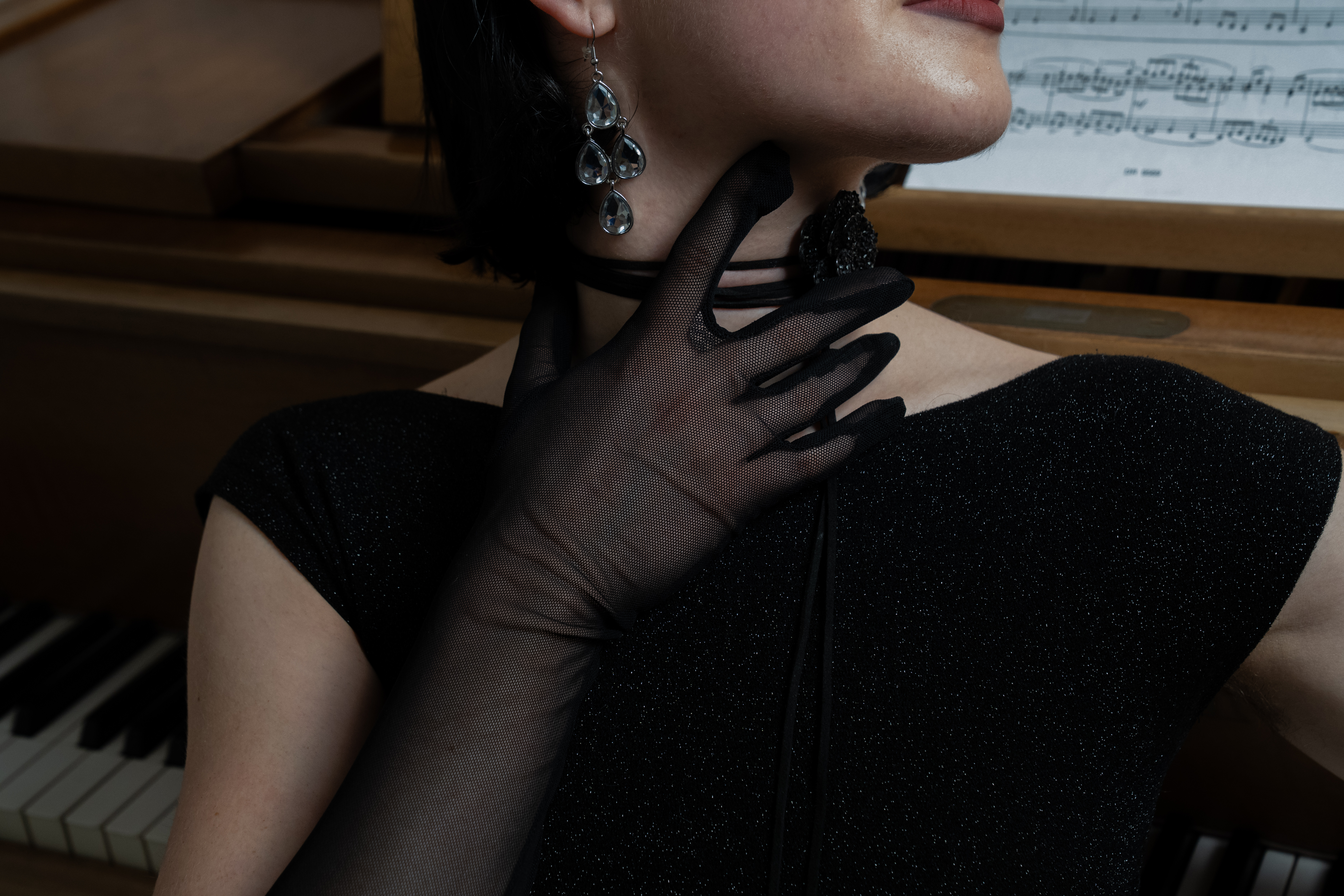 Detail — a fishnet glove at the neck, piano keys below