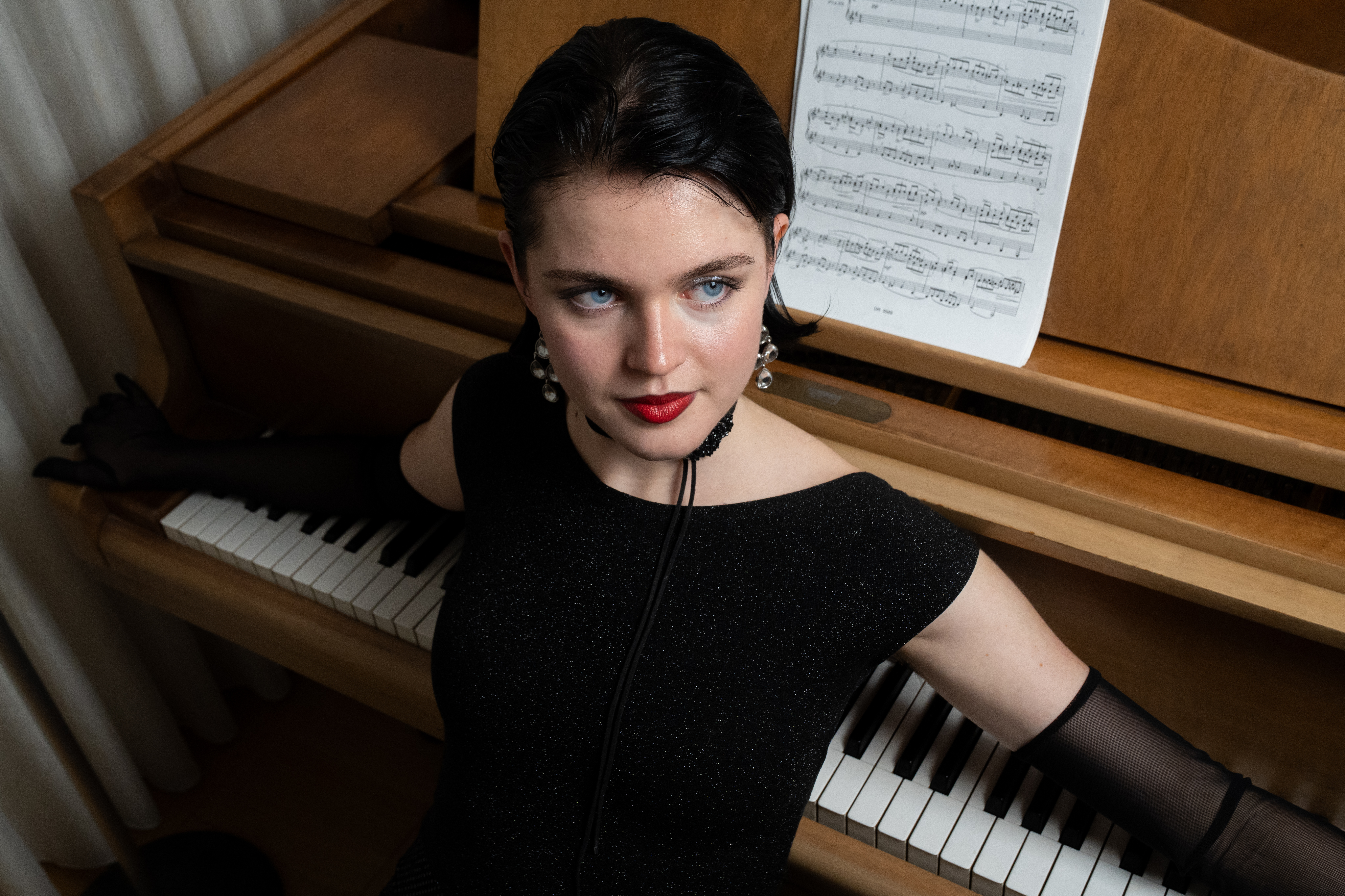 Julia at the piano in color — warm wood and red lips