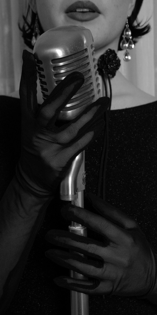 Detail — a vintage microphone in a gloved hand